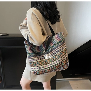 Close-up of bohemian woven tote bag with colorful geometric patterns on a shoulder model