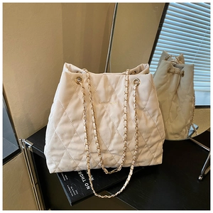 Makro-Detail der elfenbeinfarbenen Stepptasche mit goldener Kette und Steppnähten