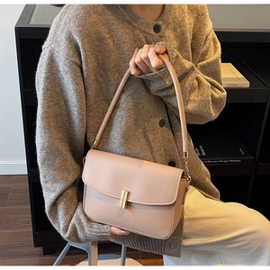 Detail of minimalist apricot shoulder bag with gold metal clasp and elegant chain strap