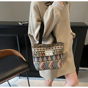Detail of colorful geometric woven tote bag with durable black handles and brand tag