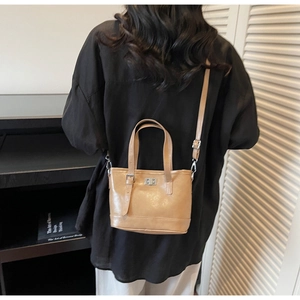 Vue arrière d'un mannequin portant un sac seau chic en cuir marron clair à boucle métal