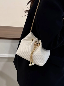 Minimalist beige corduroy bucket bag with gold chain strap and pearl drawstring detail