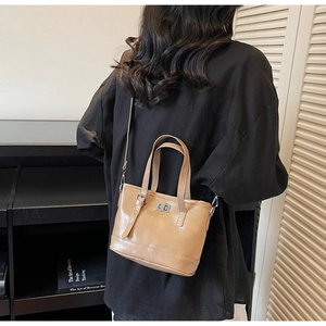 Sac seau en cuir beige porté en bandoulière dans un cadre de vie moderne avec livres