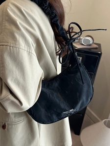 Chic black crescent shoulder bag with pleated straps and stylish side tie details