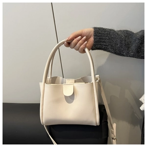 Detail of cream white leather bucket bag with top handles and adjustable strap
