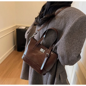 Détail du sac seau en cuir marron foncé avec fermoir rotatif argenté et bandoulière