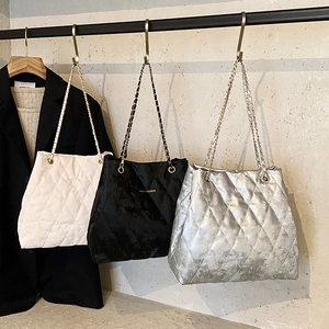 Gesteppte Tragetaschen in Weiß, Schwarz und Silber mit Kettenriemen auf einem Kleiderbügel