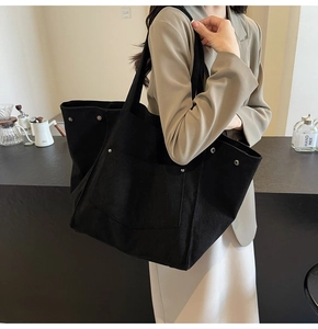 Detail view of black corduroy tote bag with silver rivets and large front pocket