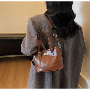 Détail macro du sac seau en cuir ciré marron brillant avec son fermoir rotatif argenté