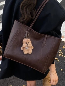 Vintage dark brown leather tote bag with plush charm shown on a stylish model in the city
