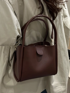 Brown lychee texture bucket bag with dual handles and gold hardware shown on a model