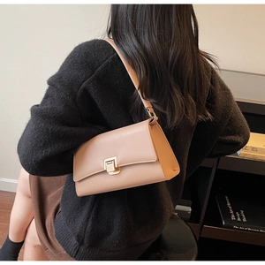Close-up of beige leather underarm bag with gold metal buckle and smooth stitching