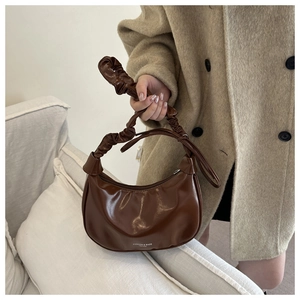 Détail du sac plissé marron foncé brillant avec anse à nœud et fermeture à glissière