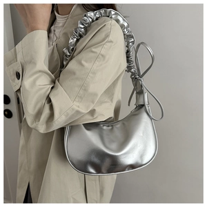 Détail de la bandoulière plissée argentée sur un sac demi-lune en cuir métallisé