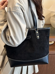 Quilted black tote bag with white contrast stitching and gold rivets for casual commute