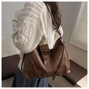 Close-up of brown faux leather tote bag with decorative buckles and soft texture details