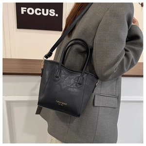 Detail of vintage black leather tote bag featuring gold logo and adjustable shoulder strap