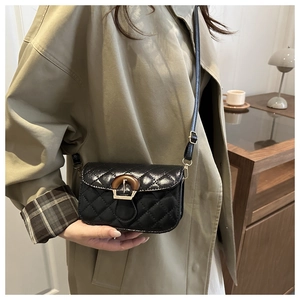 Detail of black quilted crossbody bag with unique wooden ring buckle on khaki trench coat