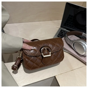 Detail showing brown quilted leather texture and metallic clasp of a small crossbody bag