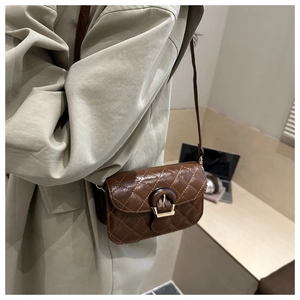 Detail of a brown quilted crossbody bag with gold hardware and patent leather texture