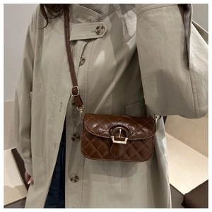 Detailed view of brown quilted crossbody bag with vintage bronze buckle and textured leather