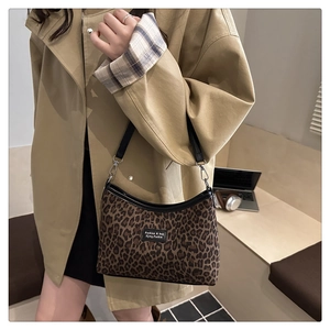 Close-up of leopard print baguette bag featuring black leather trim and silver metal hooks