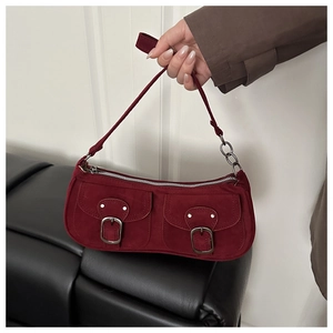 Detail of burgundy suede shoulder bag with two front pockets and silver buckles