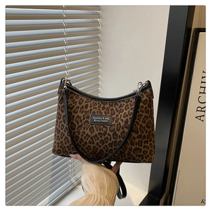 Dettaglio borsa tote leopardata con finiture in pelle nera e toppa con logo del brand