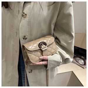 Detail of beige quilted crossbody bag featuring a vintage wooden ring buckle and gold hardware