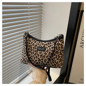 Dettaglio della borsa tote leopardata con cinturini in pelle nera e chiusura a zip