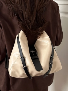 Minimalist cream leather backpack for women with black adjustable straps on a model