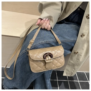 Detailed view of khaki quilted crossbody bag with unique wood-textured clasp decoration