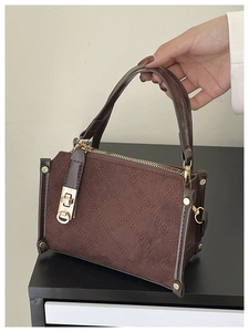 Détail d'un sac cabas matelassé marron foncé avec fermoir tournant doré et fini mat chic
