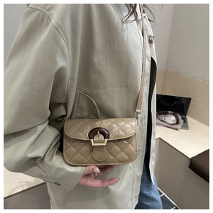Detail of light brown quilted crossbody bag with unique wood-texture buckle on model