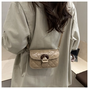 Detail of quilted crossbody bag with wooden buckle shown on a model's back