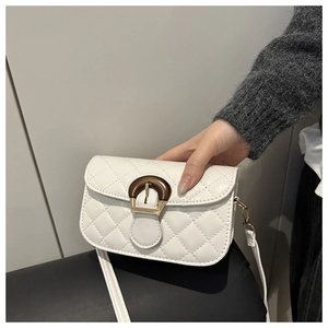 Detail view of white quilted crossbody bag featuring a unique brown D-ring resin buckle