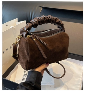 Détail du sac en daim marron avec poignée à volants en cuir et finitions métalliques dorées