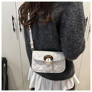 White quilted shoulder bag featuring a vintage amber buckle accent on grey knitwear