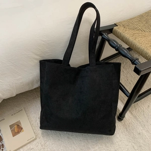 Close-up of minimalist black tote bag with premium texture on a cozy grey carpet