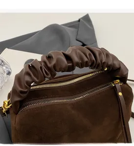 Détail du sac à main en daim marron avec poignées en cuir plissé et zips dorés