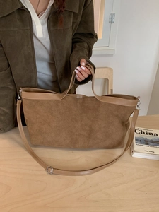 Grand sac cabas en daim marron avec anses en cuir dans un décor studio minimaliste