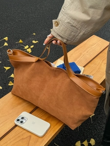 Grand sac cabas en nubuck marron sur un banc en bois décoré de feuilles d'automne rousses