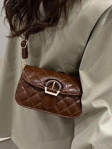 Brown quilted crossbody flap bag with gold hardware and adjustable strap on a model