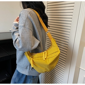 Detail of a bright yellow crescent nylon bag featuring a thick braided zipper puller