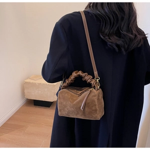 Détail du sac à bandoulière en suède avec poignée froncée et sangle réglable