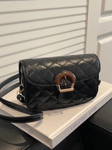 Quilted black crossbody bag with wood buckle and gold hardware on white background
