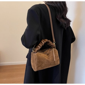 Détail du sac Boston en daim marron avec poignées plissées et bandoulière réglable