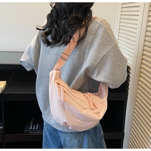 Detail view of the pink nylon crescent bag featuring double zippers and woven pullers