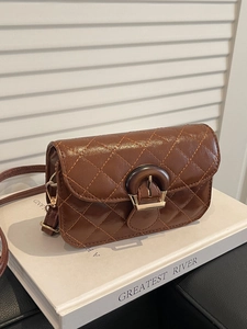 French vintage brown quilted shoulder bag with gold clasp on white book decor