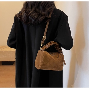 Détail du sac bandoulière en similicuir marron foncé avec une poignée plissée unique